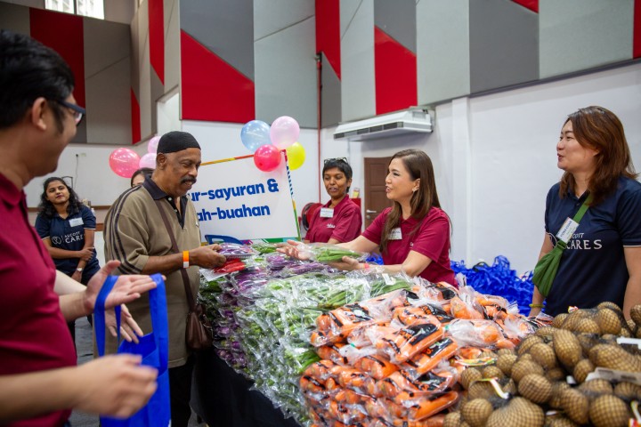 受益者在文良港Desa Rejang社区礼堂内,浏览并挑选由凯德集团员工志愿者精心布置摊位所提供的各类新鲜蔬菜与饼干